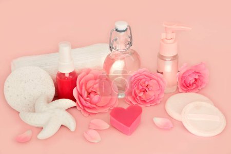 Rosenblüten Schönheitsprodukte auf rosa. Natürliche rein feminine Wellness-Behandlung für empfindliche Haut. Weibliche Inhaltsstoffe mit Seifen, Feuchtigkeit, Gel, Aromatherapie-Öl und Blumen.