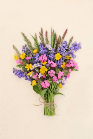 Spring wildflower posy on hemp paper with bluebell, red campion, buttercup and cuckoo flowers with wild meadow grass. Floral Beltane nature composition of natural British flowers.