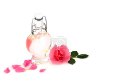 Rosenwasser mit rosa Rosenblüte mit herzförmiger Flasche. Natürliche, gesunde Hautpflege zur Hydratation der Haut, zur Verringerung von Rötungen, Irritationen, zur Behandlung von Narben, Verbrennungen, zur Wiederherstellung des ph-Gleichgewichts. Auf weißem Hintergrund.