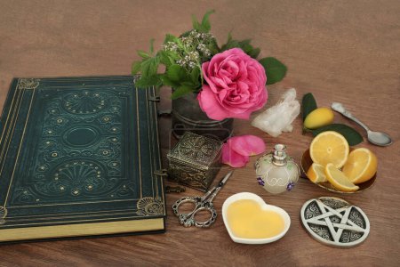 Love potion preparation for magic spell with ingredients of rose flower, quartz crystal, thyme, mint, lemon fruit, honey with book of spells. Wiccan occult magical concoction.