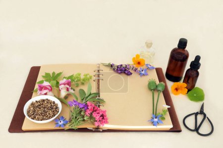 Herbal medicine preparation with flowers and herbs for natural aromatherapy treatments. Ingredients for alternative remedies with recipe notebook, essence bottles on hemp paper.