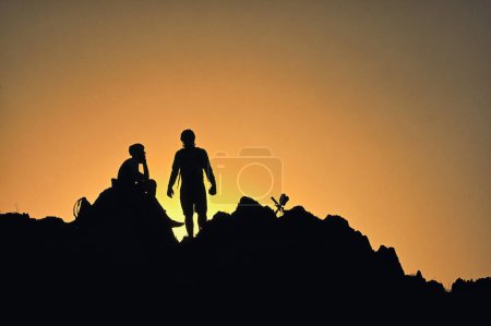 Photo for Silhouettes Of A Cyclists Standing on Clif Against The Sun in Spring Time - Royalty Free Image
