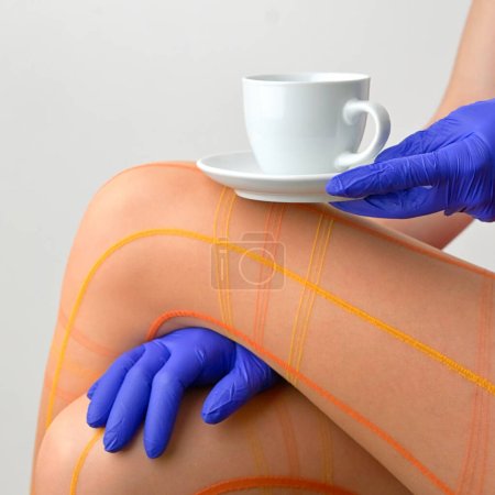 Téléchargez les photos : Résumé Une femme a une tasse de thé ou de café sur son genou et collants orange - en image libre de droit
