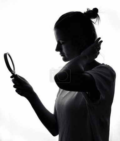 Téléchargez les photos : Une charmante silhouette de jeune fille regardant dans le miroir en studio - en image libre de droit