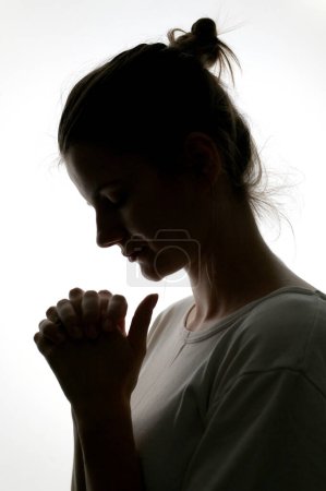 Téléchargez les photos : Profil rapproché d'une femme priant dans une silhouette isolée en studio - en image libre de droit