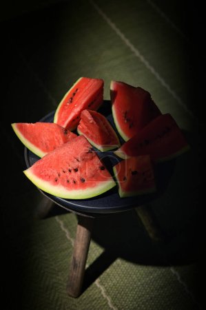 Téléchargez les photos : Sliced watermelon on a plate and old chair with natural light - en image libre de droit