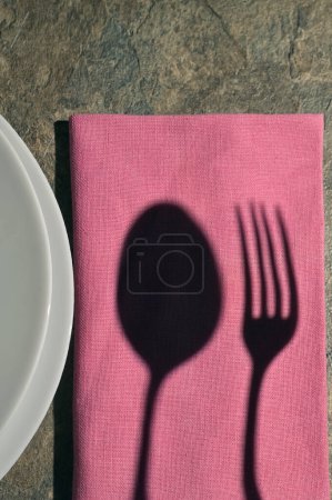 Téléchargez les photos : Assiette abstraite avec couverts d'ombre sur table en pierre - en image libre de droit