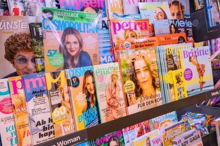 Foto per 25 luglio 2022, Munster, Germania: Molte riviste di moda, tabloid e riviste di alta qualità sul bancone del negozio in tedesco - Immagine Royalty Free