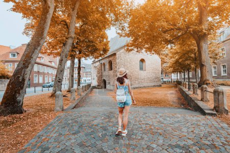 Foto de Turista mujer con mochila caminando por la vieja calle de la ciudad europea en otoño colorido o tiempo de otoño - Imagen libre de derechos