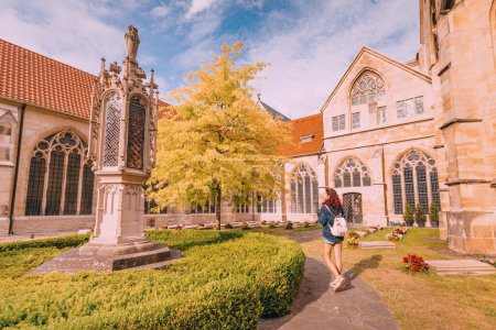 Foto de 25 de julio de 2022, Munster, Alemania: Una chica turística camina por el patio con un cementerio gótico en la catedral de San Pablo en Muenster - Imagen libre de derechos