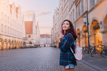 Foto de Mujer turista feliz visitando la calle Prinzipalmarkt y admirando edificios de arquitectura del casco antiguo en Munster, Alemania - Imagen libre de derechos