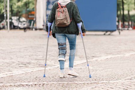 Foto de La persona camina en un vendaje especial que fija la articulación de la rodilla para la rehabilitación después de la cirugía en el menisco, ligamento o tendón - Imagen libre de derechos