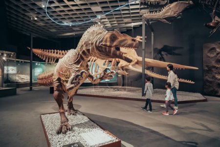 Foto de 26 de julio de 2022, Museo de Historia Natural de Munster, Alemania: Familia con niños visitando la exposición de aterradores esqueletos de dinosaurios del período Jurásico y Cretácico - Imagen libre de derechos