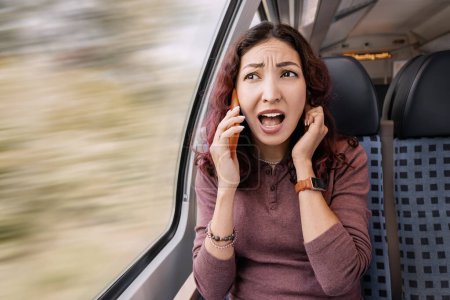 Das genervte Mädchen ist in einem Zug unterwegs und kann wegen des Lärms und eines schlechten Signals den Gesprächspartner nicht hören. Schlechte Mobilfunknetzabdeckung
