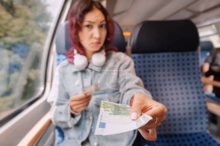 A sad girl pays a fine for a stowaway on a train or gives a bribe to a person on duty. The concept of fraud and scam in public transport