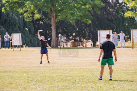 Téléchargez les photos : 30 juillet 2022, Cologne, Allemagne : Des sportifs jouent au frisbee dans le parc et se lancent un disque - en image libre de droit
