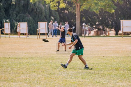 Téléchargez les photos : 30 juillet 2022, Cologne, Allemagne : Des sportifs jouent au frisbee dans le parc et se lancent un disque - en image libre de droit
