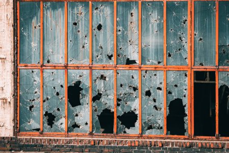 Photo for Building in industrial zone with windows broken from stones, bullets and shards. The concept of military conflict, ghettos and social theory of broken glass - Royalty Free Image