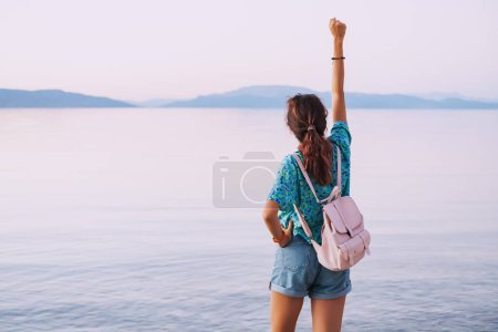 Téléchargez les photos : Fille heureuse voyageant et profitant de la vue sur le lac ou la côte de la mer pendant le coucher de soleil majestueux. Lac Egirdir, Turkiye - en image libre de droit