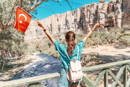 Photo for Happy girl with national Turkish flag with famous Ihlara valley in Cappadocia in the background. Travel and tourism destinations in Turkiye - Royalty Free Image