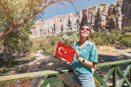 Photo for Happy girl with national Turkish flag with famous Ihlara valley in Cappadocia in the background. Travel and tourism destinations in Turkiye - Royalty Free Image