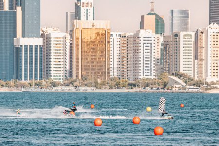 Photo for 15 January 2023, Abu Dhabi, UAE: Jet skiing is an exciting and adventurous water sport that involves riding a personal watercraft against background of skyscrapers - Royalty Free Image