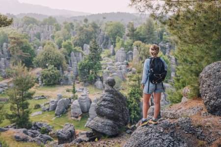Foto de Chica viajera feliz de pie en la cima del acantilado de roca con vista a los restos de piedra en Altinkaya, Turkiye. Atracciones turísticas y destinos - Imagen libre de derechos