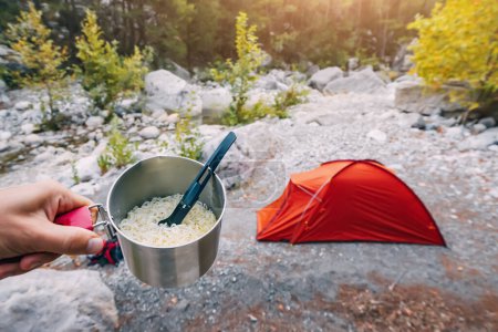 Photo for Camping fast food - noodle soup in a pot on the background of a tent in wild camping - Royalty Free Image