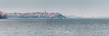 Danube river gracefully meanders past the historic Zemun district of Belgrade with Gardos tower, where charming red-roofed houses and ancient churches paint a picturesque panorama