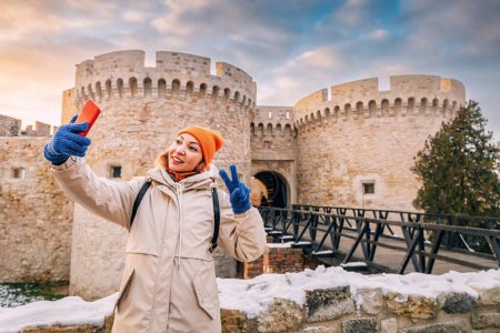 In the heart of Belgrade's Kalemegdan, a young woman captures selfie photo on her smartphone, blending modern technology with historic beauty.