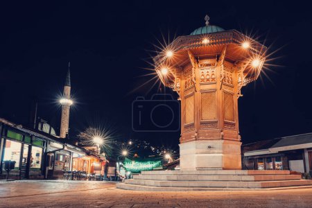 La icónica fuente Sebilj de Sarajevo: un símbolo del rico patrimonio de la ciudad, iluminado contra el cielo nocturno en Bascarsija distict