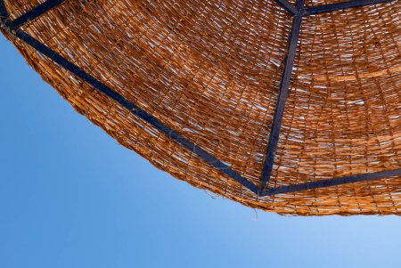 Téléchargez les photos : Travel and vacation concept. A fragment  of a reed sunshade against a clear, blue sky. Red Sea, Egypt - en image libre de droit