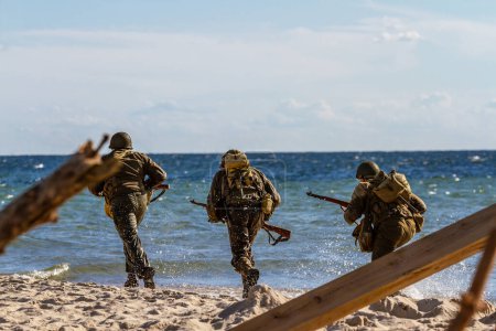 Foto de Reconstrucción histórica. Soldados de la división de infantería de la Segunda Guerra Mundial corren por la playa. Hel, Polonia - Imagen libre de derechos
