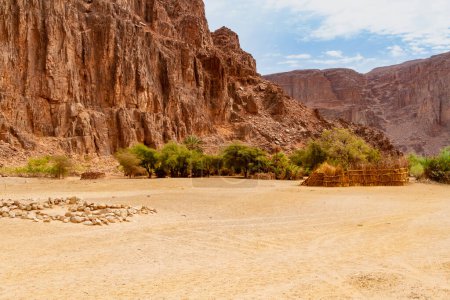 Foto de Pueblo Tuareg. Cabañas redondas y dependencias construidas de una manera tradicional caña. Oued Aharhar Gorge. Cañón Aharghar, Parque Nacional Tassili n 'Ajjer, Djanet, Argelia, África. - Imagen libre de derechos
