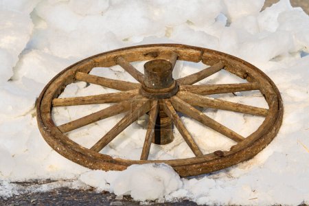 Foto de Una vieja rueda de carro. Destruir la rueda de madera de un carro tirado por caballos se encuentra descartado en la nieve. - Imagen libre de derechos