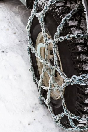 Téléchargez les photos : Ferme là. Chaînes d'hiver d'antidérapant sur une roue de voiture. Conduite sûre dans la neige profonde dans la route d'hiver. - en image libre de droit