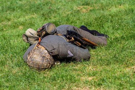 Téléchargez les photos : Reconstruction historique. Soldat blessé ou mort de la Seconde Guerre mondiale Wehrmacht couché sur l'herbe Vue de dos. - en image libre de droit