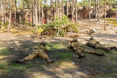 Reconstruction of battle from the Second World War. American paratrooper soldiers during combat in the forest. View from the back