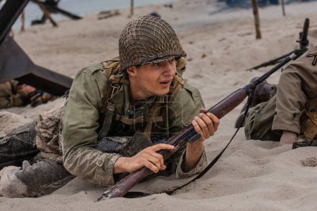 Historical reconstruction. An American infantry soldier from the World War II  fighting on the beach. 
