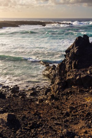 Black volcanic rocks on the Atlantic coast at sunset. Playa de las Malvas, Lanzarote, Canary Islands, Spain