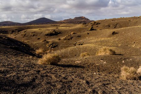 Trail around Cuervo volcano. "Malpais" -  barren and stony  field of lava. Cuervo volcano. Lanzarote, Canary Islands, Spain