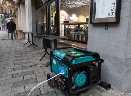 Photo for Due to the lack of power as a result of the blackout, a power generator has been installed on the sidewalk near the fish store to keep it running. - Royalty Free Image