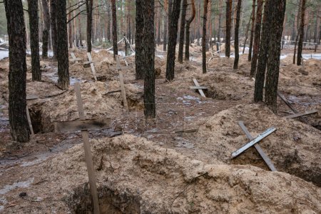 Téléchargez les photos : IZIUM, UKRAINE - mars 2023 : Des croix sont vues sur une tombe forestière après une exhumation dans la ville d'Izium, récemment libérée par les forces ukrainiennes, dans la région de Kharkiv, en Ukraine. - en image libre de droit