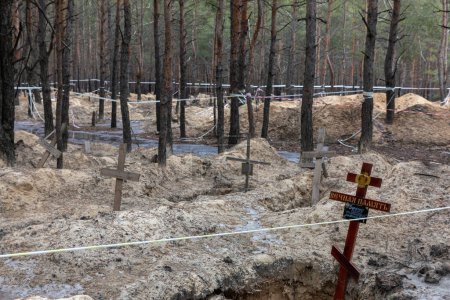 Foto de IZIO, UCRANIA - Mar. 03, 2023: Las cruces se ven en un sitio de fosas forestales después de una exhumación en la ciudad de Izium, recientemente liberada por las fuerzas ucranianas, en la región de Kharkiv, Ucrania. - Imagen libre de derechos