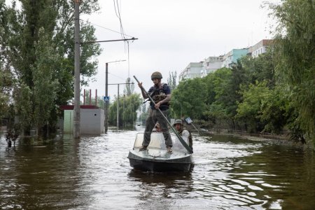Téléchargez les photos : KHERSON, UKRAINE - Jun. 2023 : Volontaires et sauveteurs se déplacent en bateau dans les rues inondées de Kherson - en image libre de droit