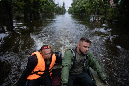 Téléchargez les photos : KHERSON, UKRAINE - Jun. 2023 : Volontaires et sauveteurs se déplacent en bateau dans les rues inondées de Kherson - en image libre de droit