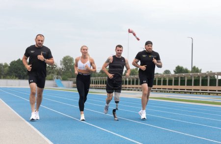 Foto de KYIV, UCRANIA - Julio. 05, 2023: Un atleta con una pierna protésica se ve corriendo en un grupo en una pista de atletismo en el estadio - Imagen libre de derechos