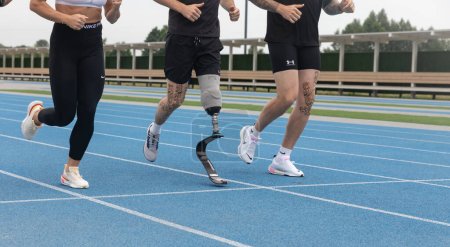 Foto de KYIV, UCRANIA - Julio. 05, 2023: Un atleta con una pierna protésica se ve corriendo en un grupo en una pista de atletismo en el estadio - Imagen libre de derechos