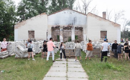 Téléchargez les photos : YAHIDNE, UKRAINE - 8 JUILLET : Les bénévoles de l'organisation "Repair Together" sont débarrassés des décombres d'une maison de culture locale endommagée par la guerre, nettoyant et empilant les briques pour les réutiliser. - en image libre de droit