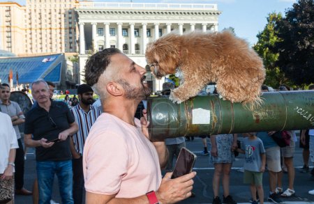 Téléchargez les photos : KYIV, UKRAINE - 24 août 2023 : Les visiteurs de l'exposition prennent des photos du chien planté sur le canon d'un char russe brûlé. - en image libre de droit